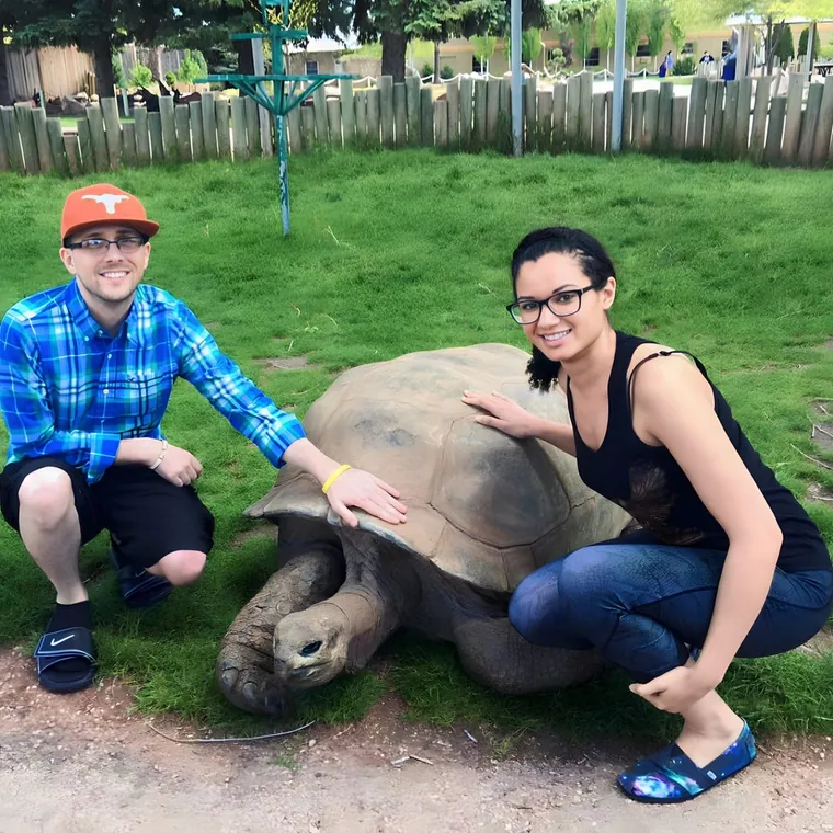 William Horschak crouched beside a giant tortoise on the grass